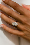 Hand wearing a diamond ring on a neutral background