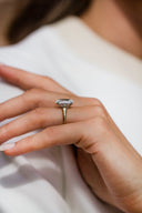 Close-up of a hand wearing a diamond ring on a white fabric background