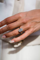 Close-up of a hand wearing a diamond ring on a neutral background