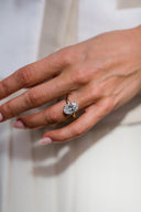 Close-up of a hand wearing a diamond ring on a plain background